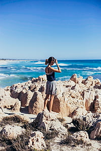 woman standing on rocks near sea thumbnail