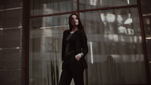selective focus photography of woman in black scoop neck longsleeve and pants standing behind on clear glass wall thumbnail
