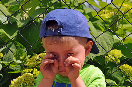 portrait photo of boy standing against mesh fence thumbnail