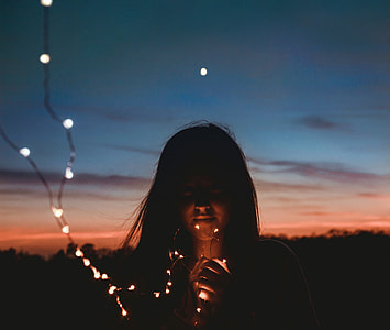 woman holding white string lights during golden hour thumbnail