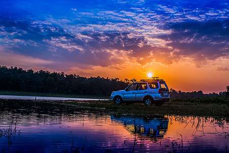 landscape photo of gray SUV in lake during sunset thumbnail