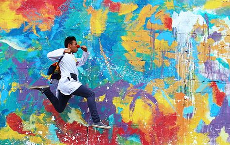 man beside assorted-color wall mural during daytime thumbnail