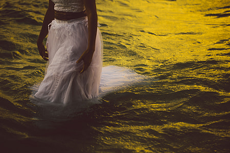 woman wearing white walking on body of water thumbnail