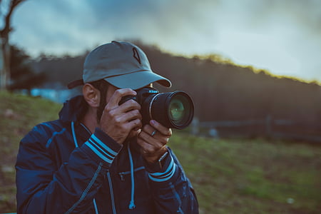 man on green grass field taking photo \ thumbnail