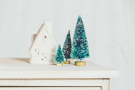 white ceramic house figurine and pine tree figurine on table thumbnail