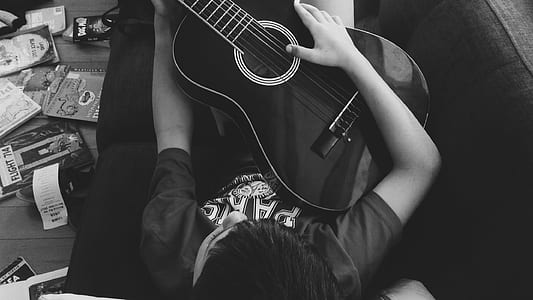 Man Playing Guitar Lying on Couch in Grayscale Photography thumbnail