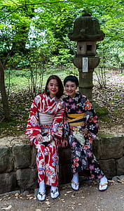 two woman taking selfie behind green leafed trees thumbnail