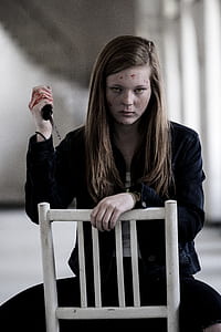woman holds knife while sitting in chair thumbnail