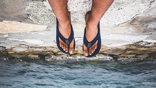 person sitting on cliff wearing flip-flops thumbnail