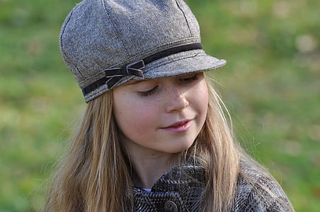 close-up photography of girl wearing grey coat and grey cap during daytime thumbnail