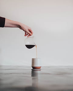 person pouring black liquid on white ceramic cup thumbnail