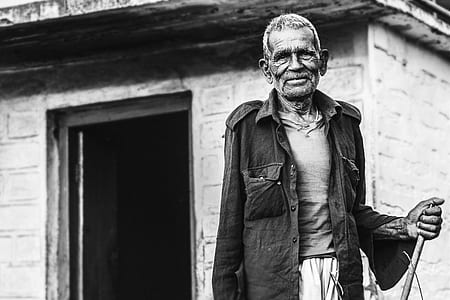 Man Wearing Button-up Shirt Standing Near Concrete House Greyscale Photo thumbnail