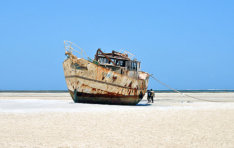 photo of white and brown ship on sand thumbnail