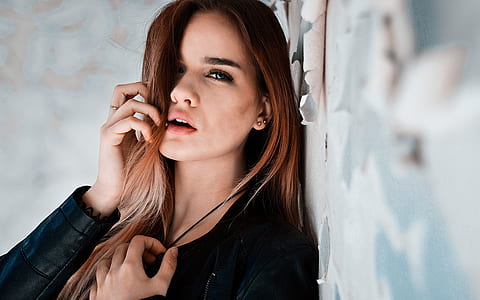 woman wearing black leather jacket while leaning on wall thumbnail