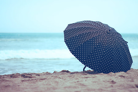 blue and white polka-dot umbrella on shore at daytime thumbnail