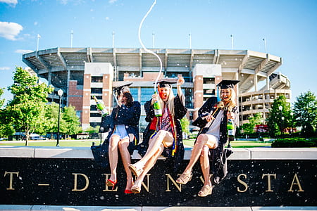 three women sitting on concrete wall thumbnail