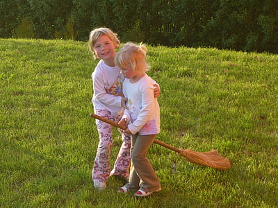 girl riding broom beside smiling standing girl during daytime thumbnail