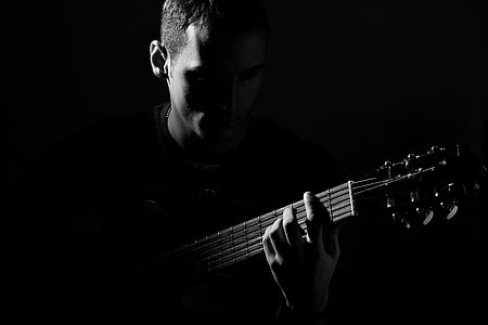 grayscale photography of man playing guitar thumbnail