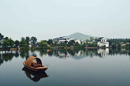 brown canoe at middle of lake near houses thumbnail