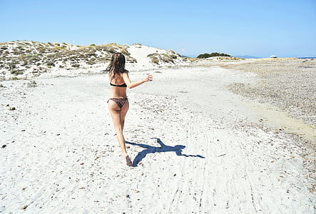 woman in black bikini running on sand during daytime thumbnail