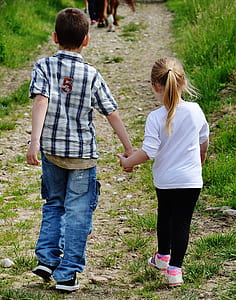 boy and girl holding hands walking on brown pathway thumbnail