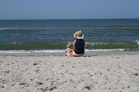 woman and baby sitting on shore thumbnail