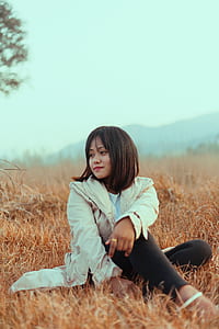 woman sitting on brown grass field thumbnail