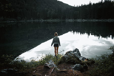 woman standing on grasses in front of lake thumbnail