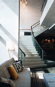 tufted gray sofa and throw pilows near stairs thumbnail