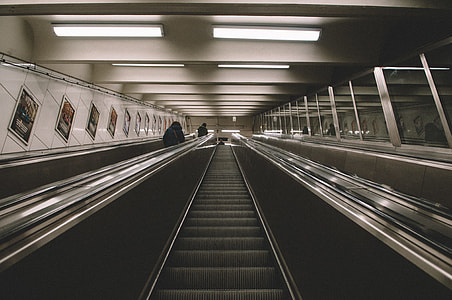 photo of two people standing beside escalator thumbnail
