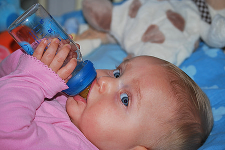 toddler holding feeding bottle while drinking thumbnail