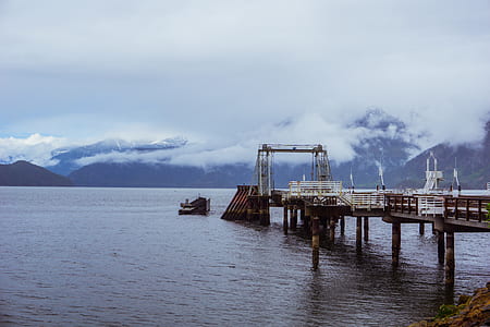 dock on body of water with mountains in the background thumbnail