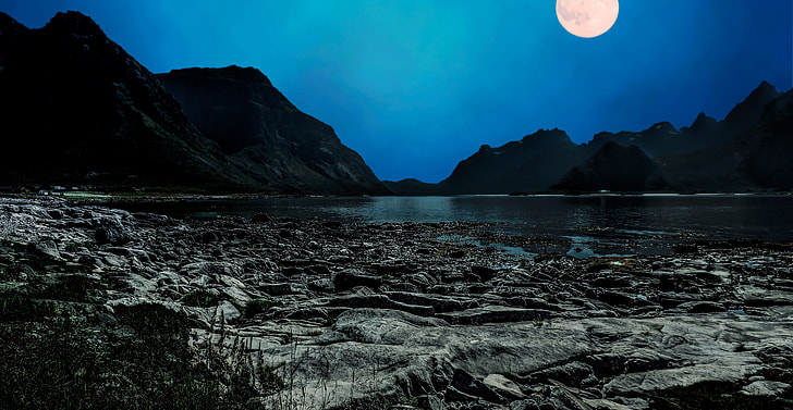 calm water of the ocean behind mountains under fullmoon