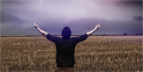 man standing on dried leaf field raising hand thumbnail