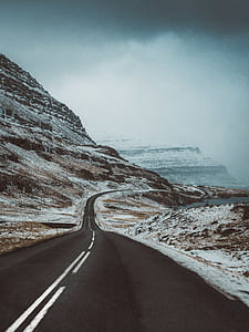 empty pave road between snowy mountains thumbnail