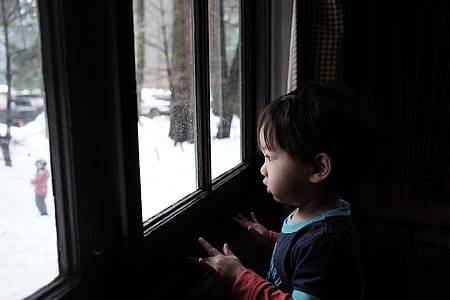 boy wearing blue top looking outside window thumbnail