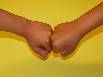 close-up photo of two human fists on yellow surface thumbnail