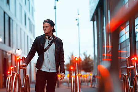 man standing beside metal rails between buildings thumbnail