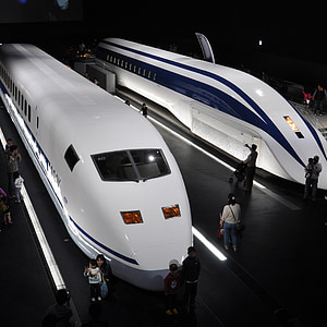 two white bullet trains surrounded by people thumbnail