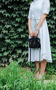 Woman Holding Black Leather Bag Beside Bush thumbnail