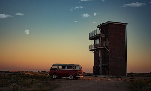 red and white Volkswagen T2 van parked near brown bricked building thumbnail