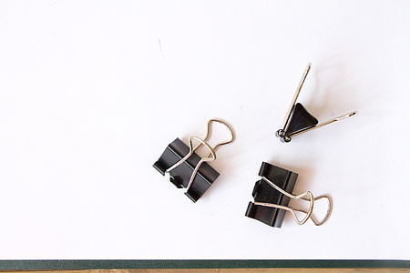 three black paper clips on white surface thumbnail