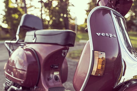 maroon Vespa motor scooter on road thumbnail