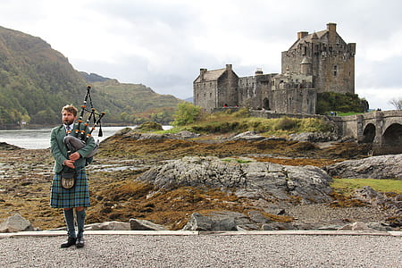 man holding bagpipe near castle thumbnail