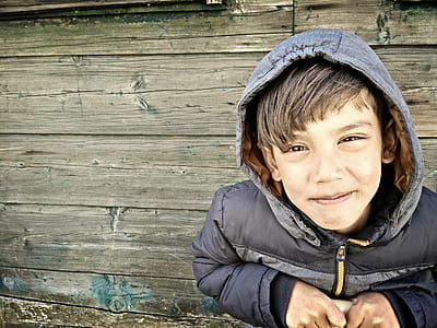 boy smiling while sitting near wall thumbnail
