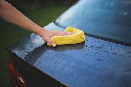 person holding yellow textile beside black vehicle thumbnail