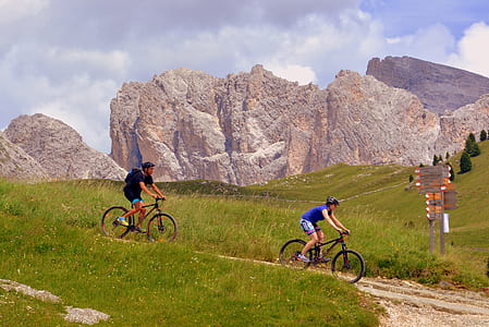 two men riding on bicycles near rocky mountain during daytime thumbnail