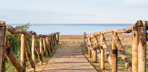empty wooden pathway leading towards ocean thumbnail