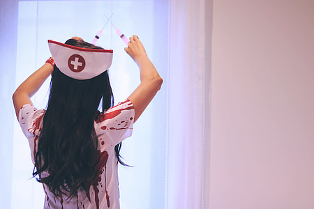 photography of woman wearing white and red Nurse costume while holding two white plastic syringe thumbnail