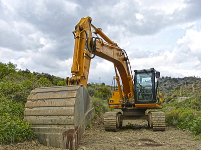 excavator beside green plants under cloudy sky thumbnail